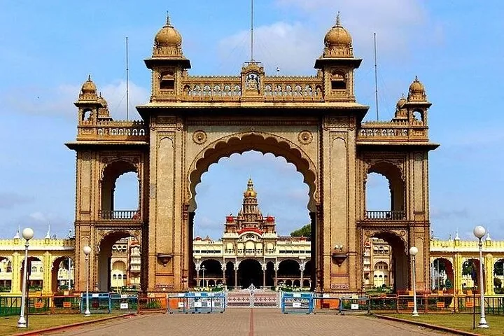 Das prächtige, bogenförmige Eingangstor zum Mysore-Palast vor blauem Himmel.