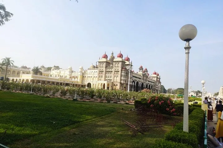 Ein weiter Blick auf den Mysore-Palast und die umliegenden grünen Gärten an einem sonnigen Tag.