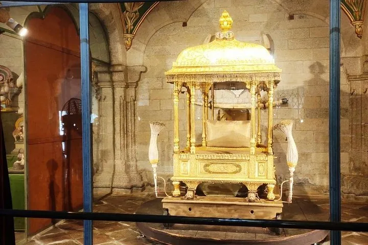 Eine verzierte goldene Kutsche in einer Glasvitrine in einem Museum.