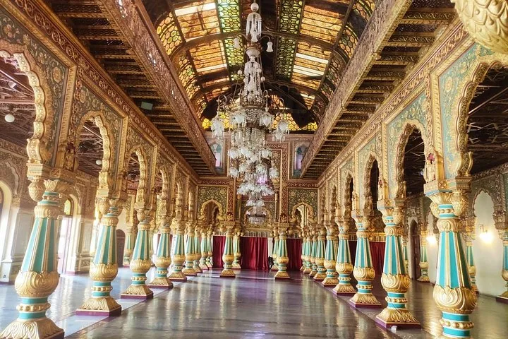Das prunkvolle Interieur des Mysore-Palasts mit türkisfarbenen Säulen und großen Kronleuchtern.